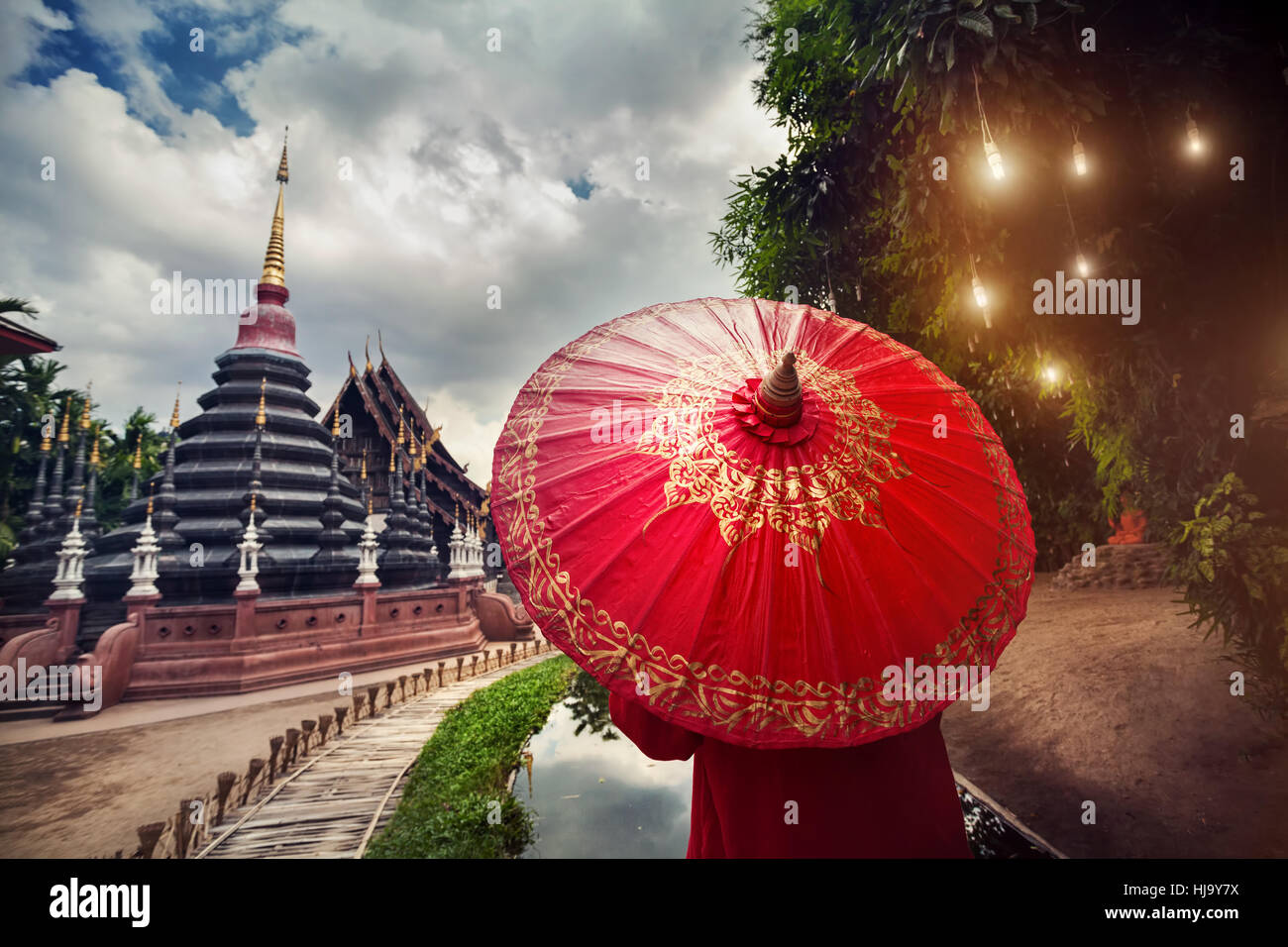 Donna con turistico rosso tailandese tradizionale ombrellone in nero tempio Wat Phan Tao in Chiang Mai Thailandia Foto Stock