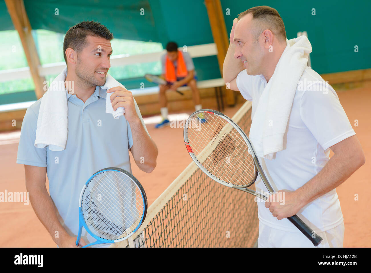 Gli uomini in chat sul campo da tennis Foto Stock