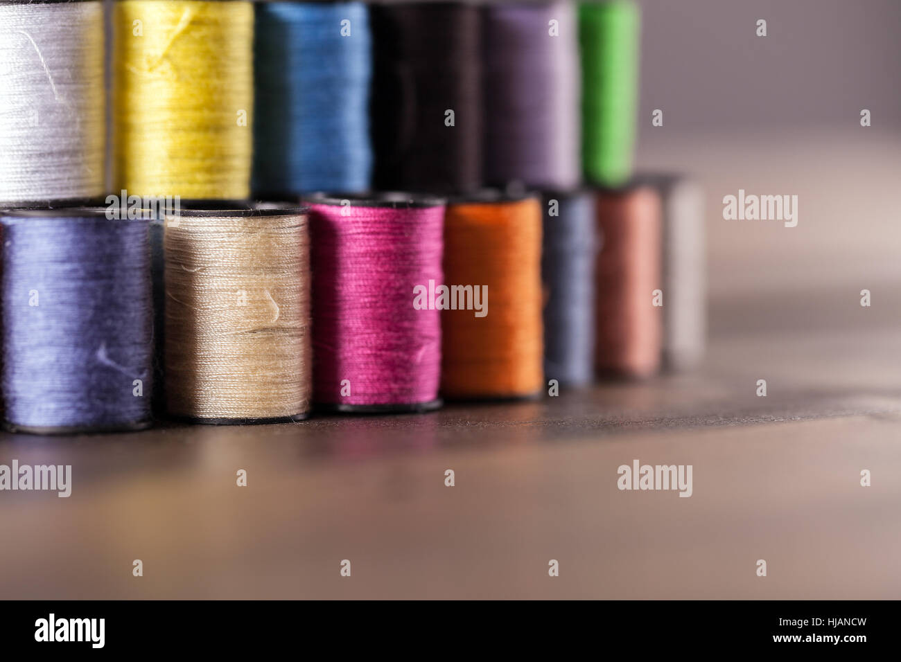 Colorate di bobine di cotone foderato e impilata insieme in una fila e visualizzati in corrispondenza di un angolo per creare profondità di campo Foto Stock
