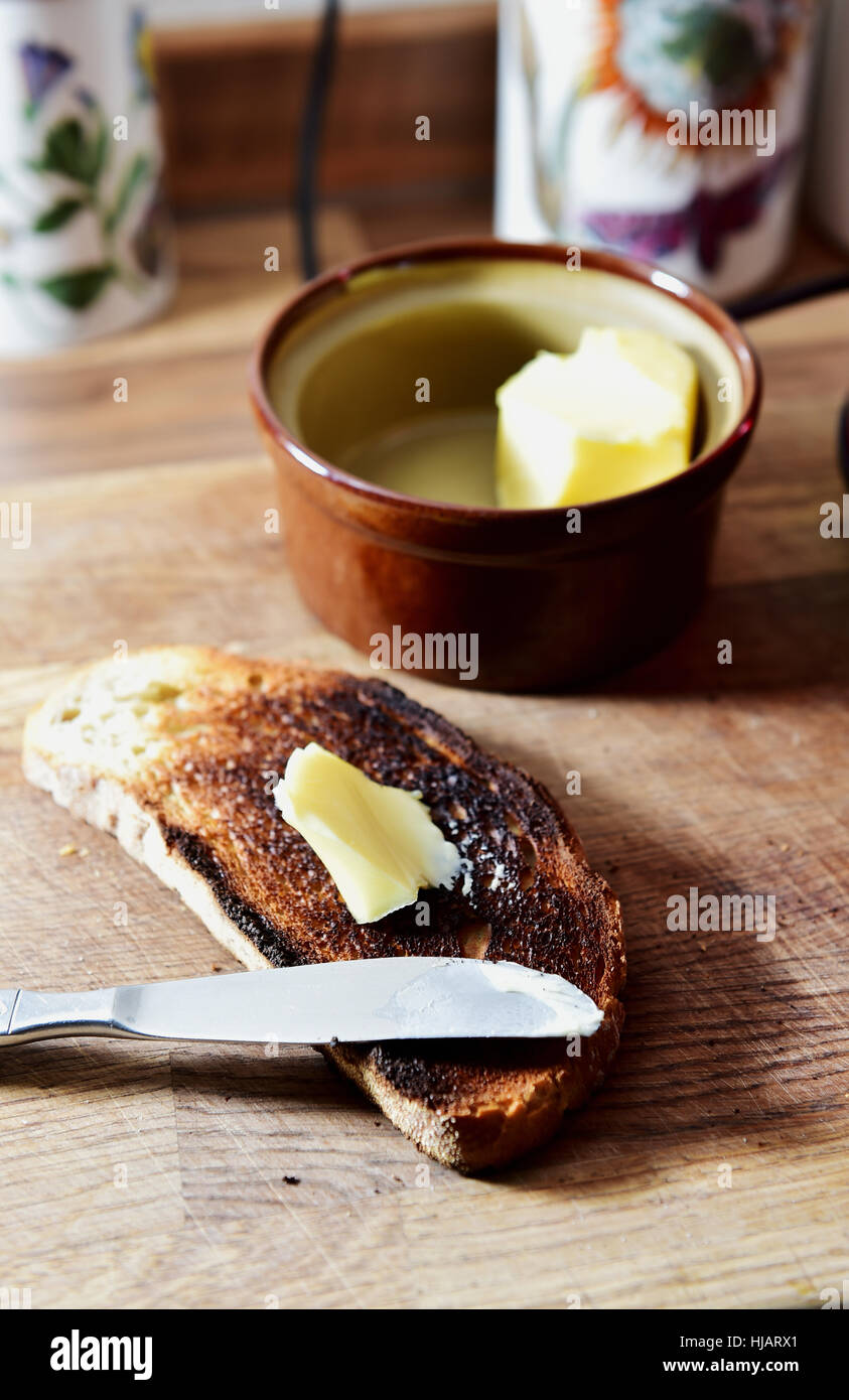 Fette di bruciato toast bianchi con coltello e burro Foto Stock