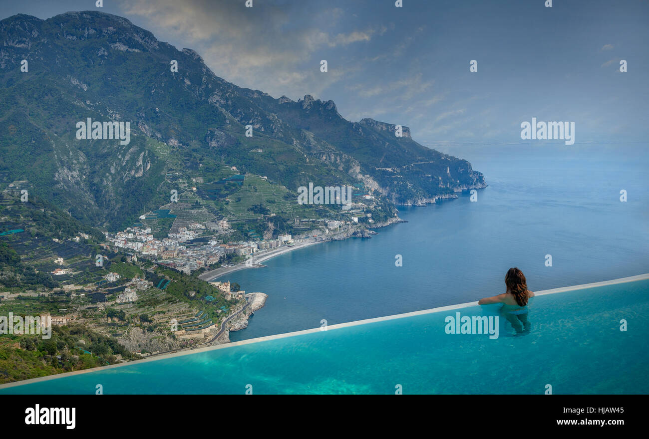 Vista posteriore della donna che guarda alla costa da piscina infinity, Ravello, Amalfi, Italia Foto Stock
