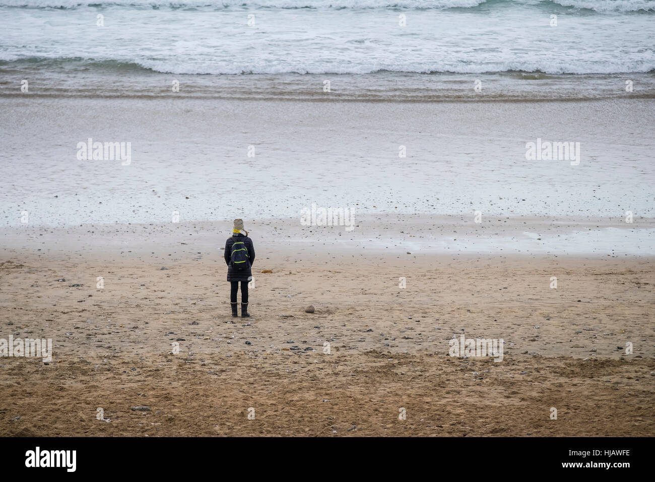 Una donna in piedi da sola sulla Fistral Beach in Newquay, Cornwall, Inghilterra, Regno Unito. Foto Stock