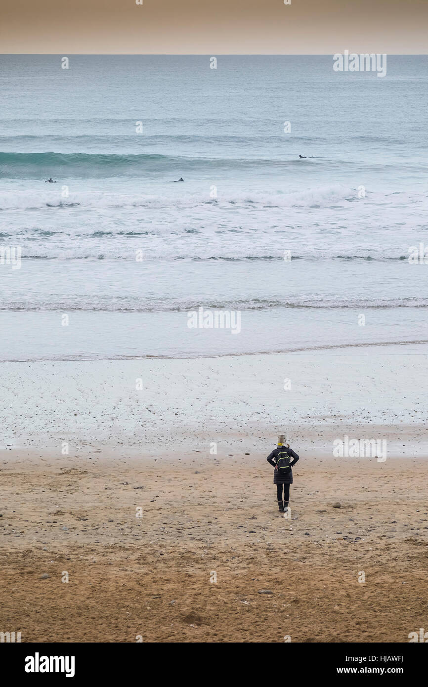 Una donna in piedi da sola sulla Fistral Beach in Newquay, Cornwall, Inghilterra, Regno Unito. Foto Stock