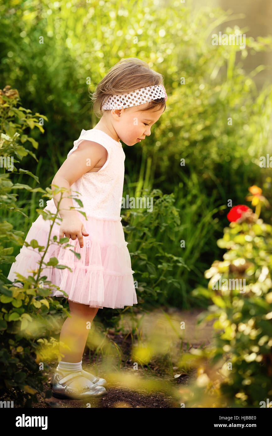 Adorabile bambina esplorando un bellissimo giardino Foto Stock