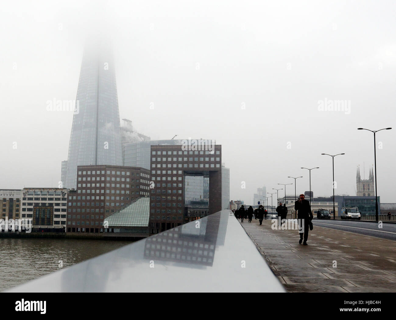 Pedoni cross London Bridge con il Coccio avvolta nella nebbia dietro di loro, come nebbia fitta causato interruzioni di viaggio attraverso il sud dell'Inghilterra, con migliaia di passeggeri aerei rivolta verso le cancellazioni e ritardi. Foto Stock