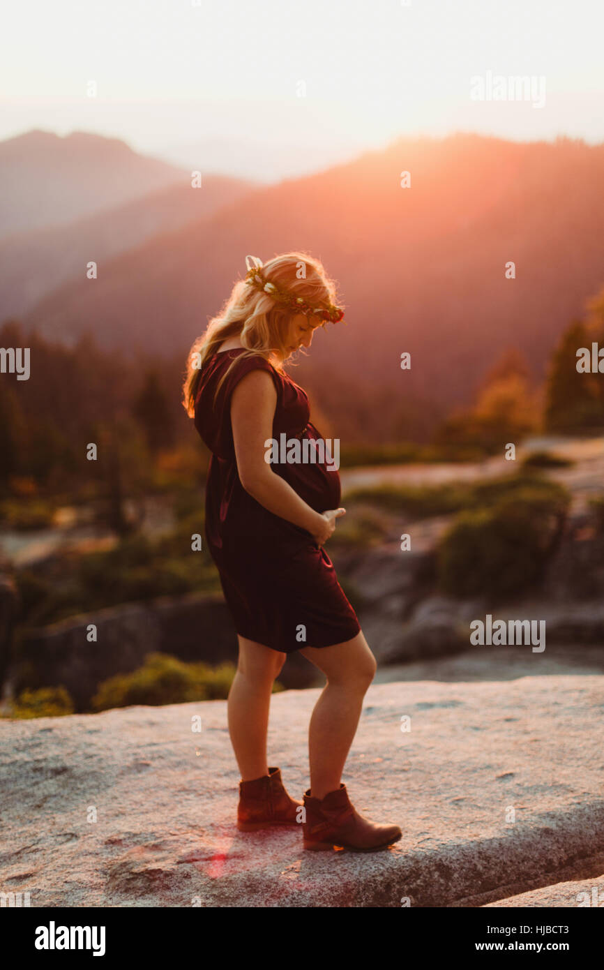 Donna incinta in montagne di toccare lo stomaco, il Sequoia National Park, California, Stati Uniti d'America Foto Stock