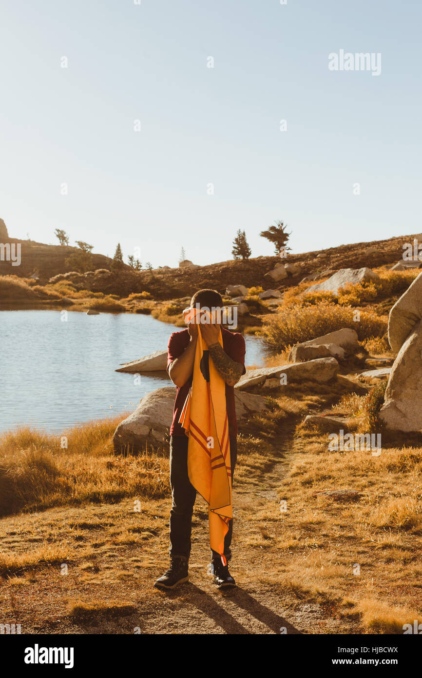 Giovane maschio escursionista dal lago faccia di essiccazione con asciugamano, minerale re, Sequoia National Park, California, Stati Uniti d'America Foto Stock