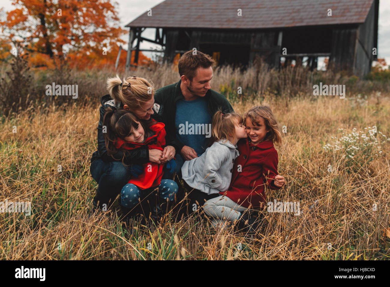 Metà adulto famiglia con tre figlie insieme in campo rurale Foto Stock