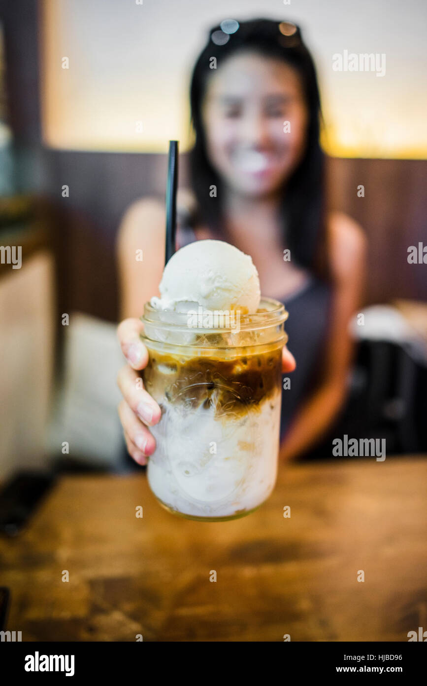 Giovane donna azienda caffè galleggiante in azienda agricola alla tavola, Bangkok, Thailandia Foto Stock