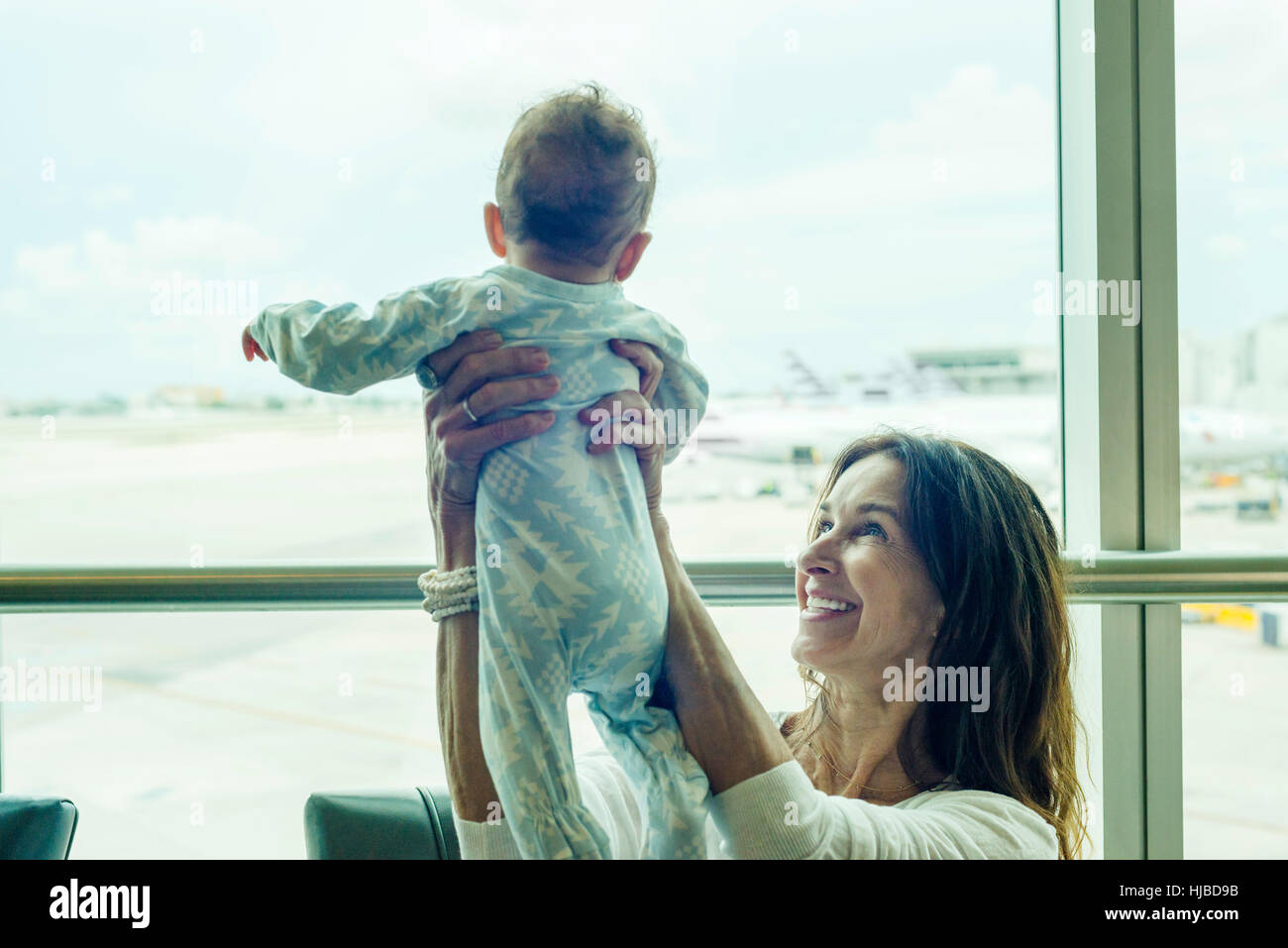 Nonna baby di sollevamento a metà in aria all'aeroporto Foto Stock