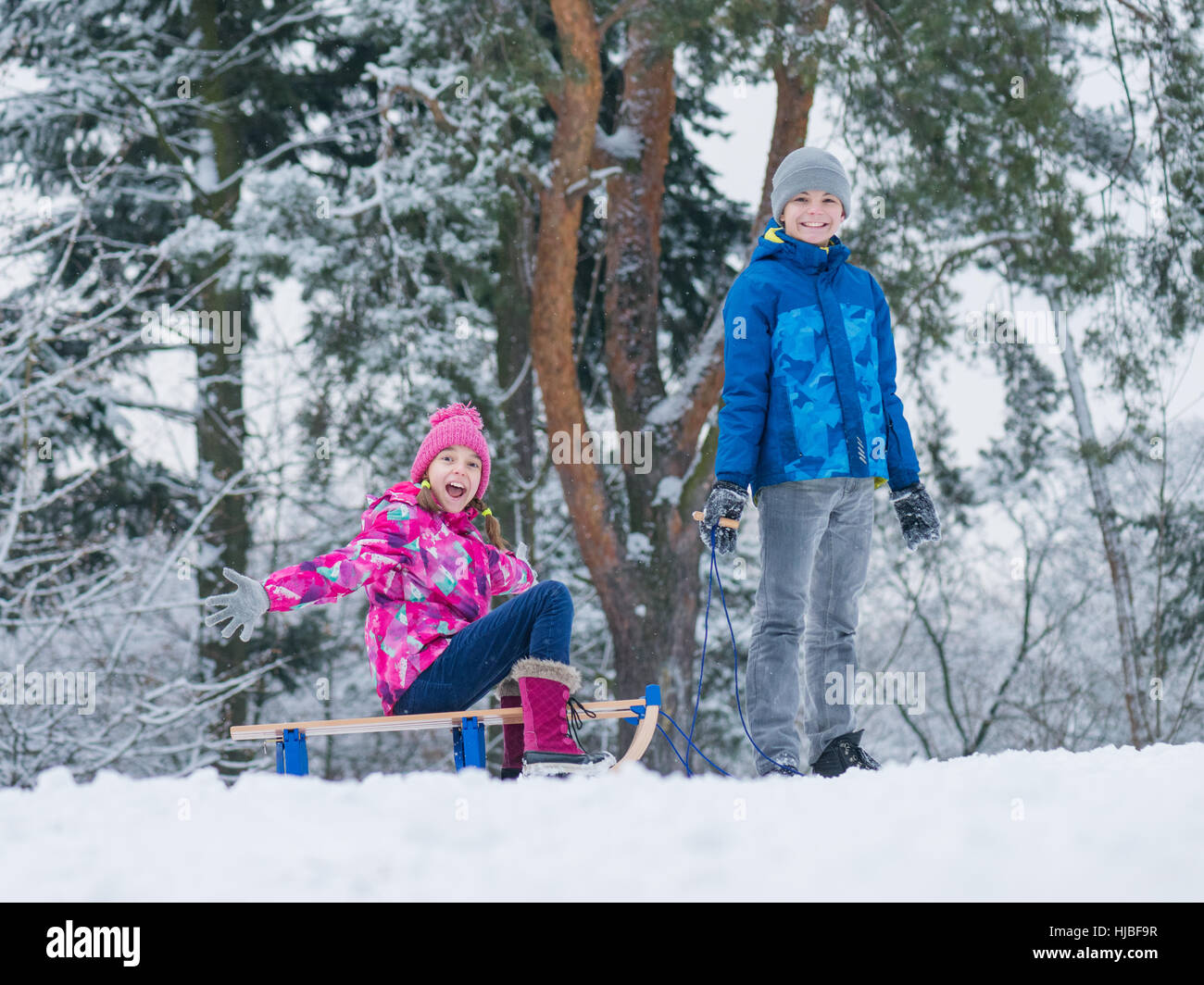 Bambino giocare nella neve con slitta Foto Stock