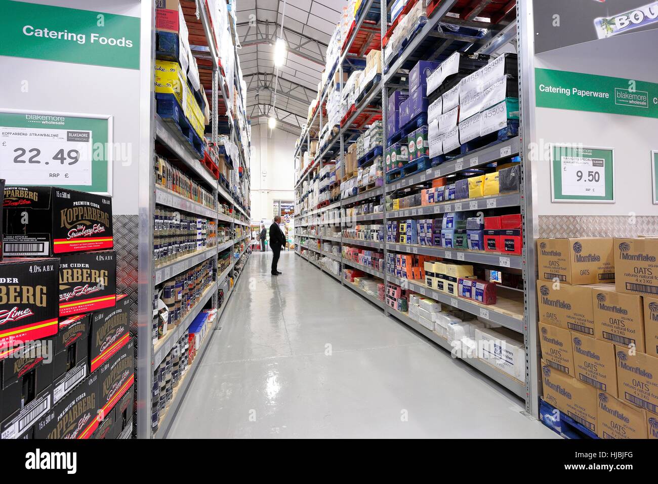 Uomo in piedi nella corsia dei prodotti asciutti sezione di un grossista. Foto Stock
