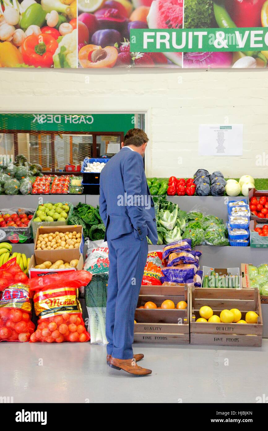 Uomo in tuta blu alla ricerca della frutta e della verdura sezione di un grossista di prodotti alimentari. Foto Stock