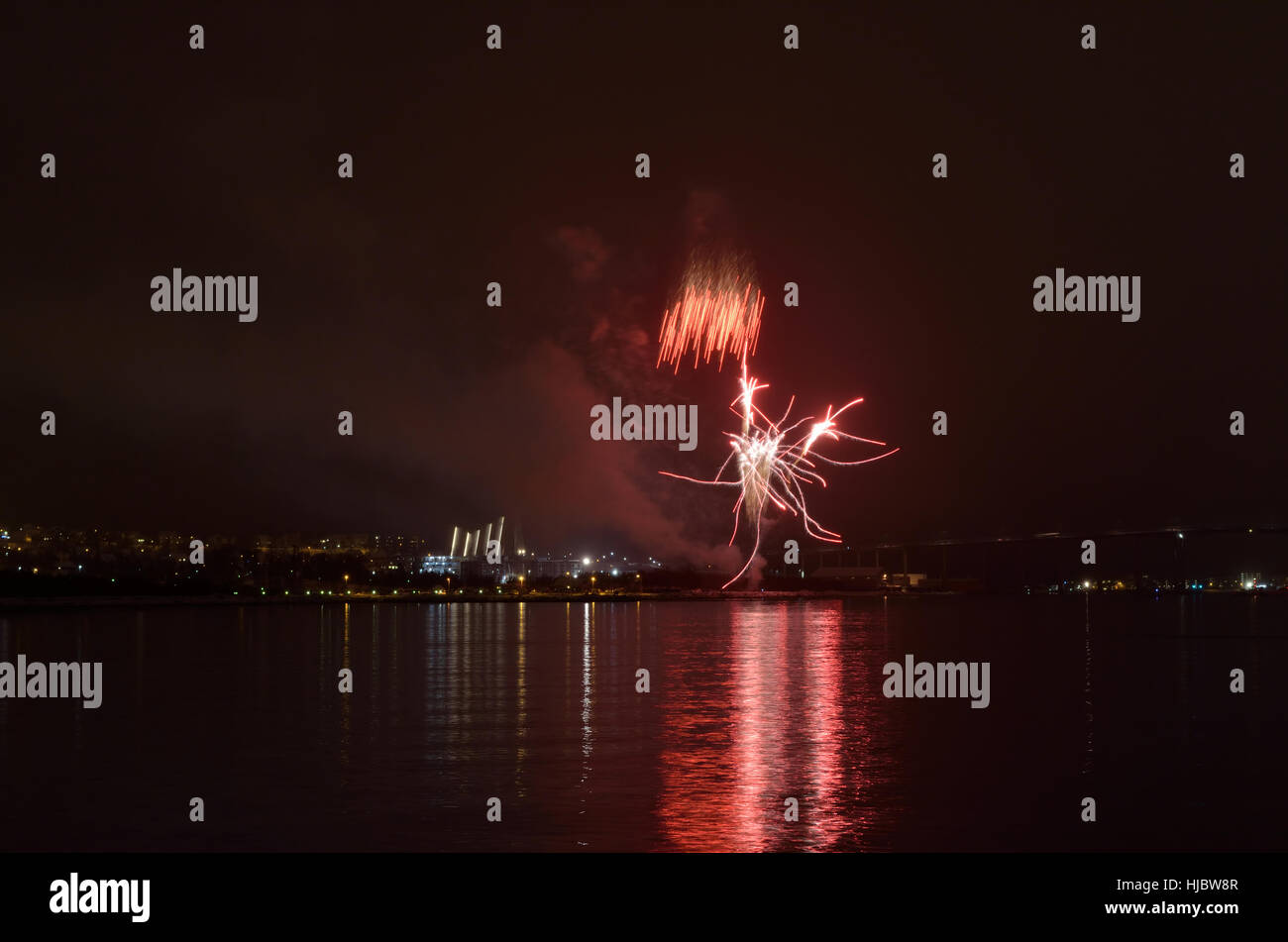 Bellissimi fuochi d' artificio sul cielo notturno in tromsoe città con bridge, cattedrale e colorato la riflessione sul fiordo a freddo della superficie dell'acqua Foto Stock