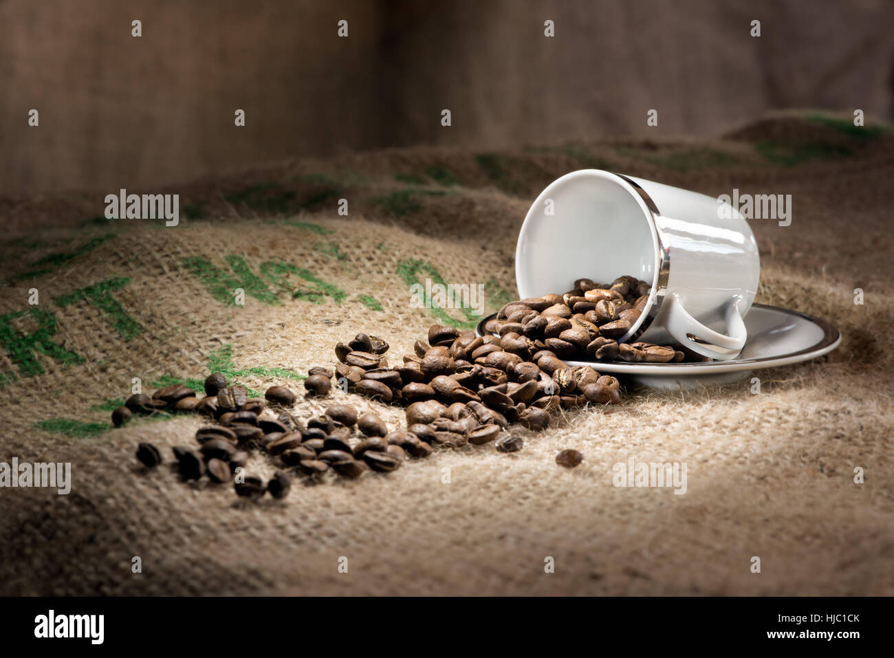 Un studio, ancora la vita di una tazza di caffè su un piattino con un bastoncino di cannella, fagioli arrosto e i biscotti su una stuoia di Hesse Foto Stock