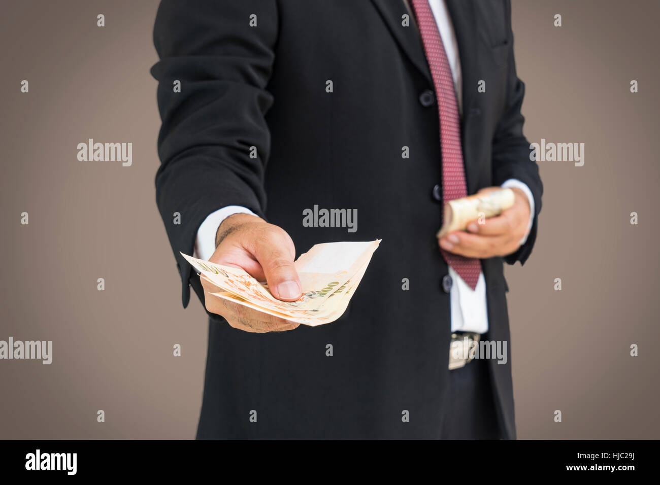 Scena di busineesman dare i soldi a voi su sfondo grigio - possono essere utilizzate per la visualizzazione o montaggi sul prodotto o il concetto di corruzione Foto Stock