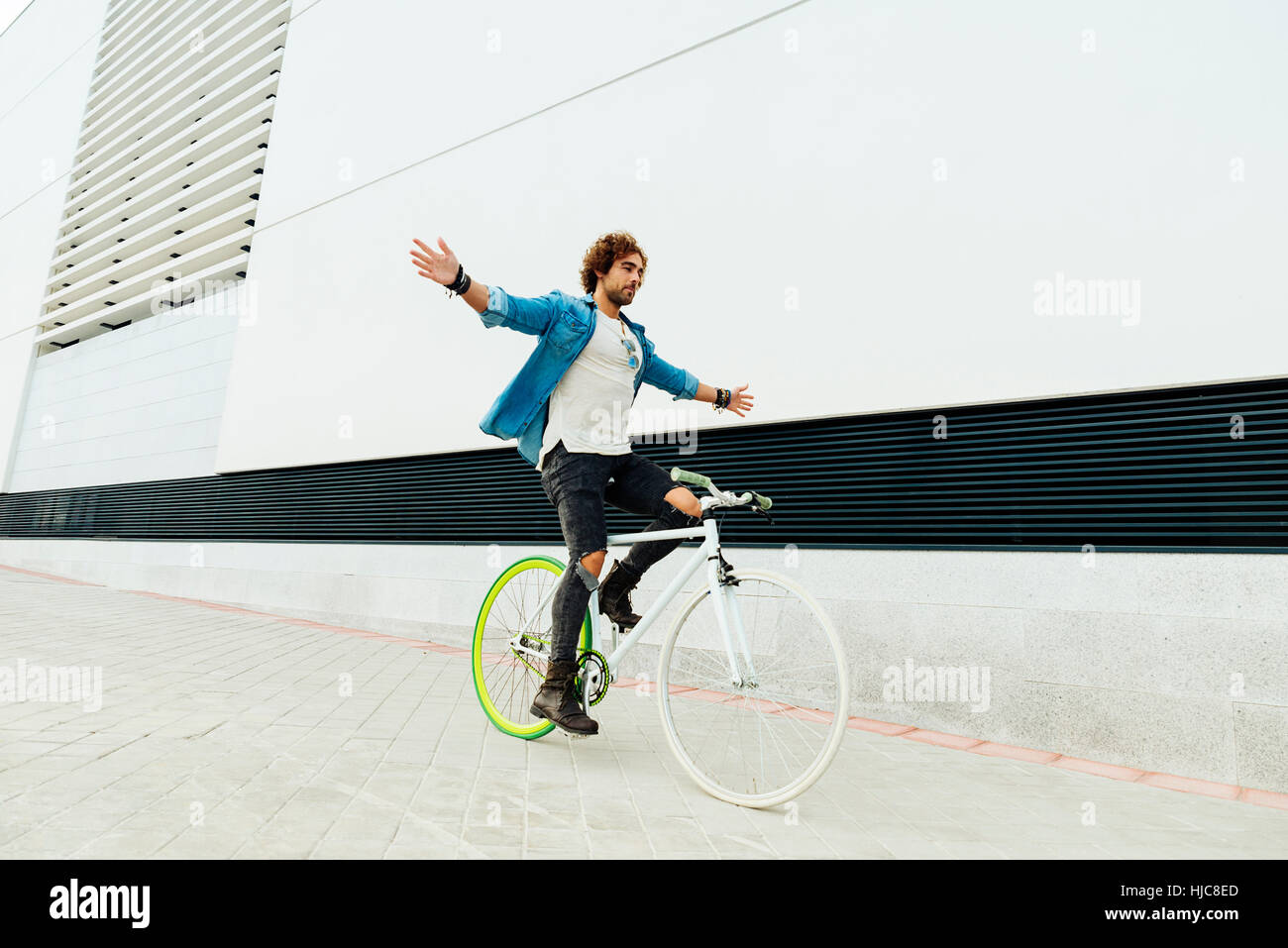 Bel giovane in bici senza mani in città. Concetto di bicicletta Foto Stock