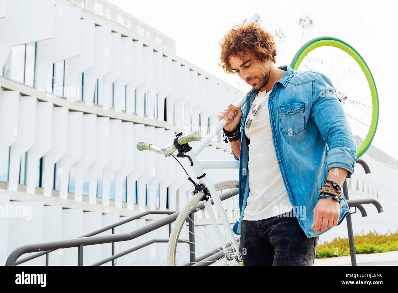 Bel giovane con ingranaggio fisso in bicicletta in strada. Foto Stock