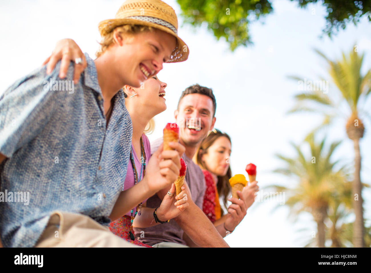 Quattro amici adulti a ridere e mangiare il gelato coni, Maiorca, SPAGNA Foto Stock