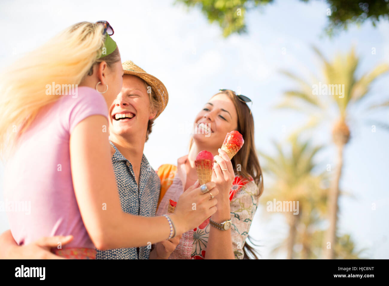 Tre amici adulti a ridere e mangiare il gelato coni, Maiorca, SPAGNA Foto Stock