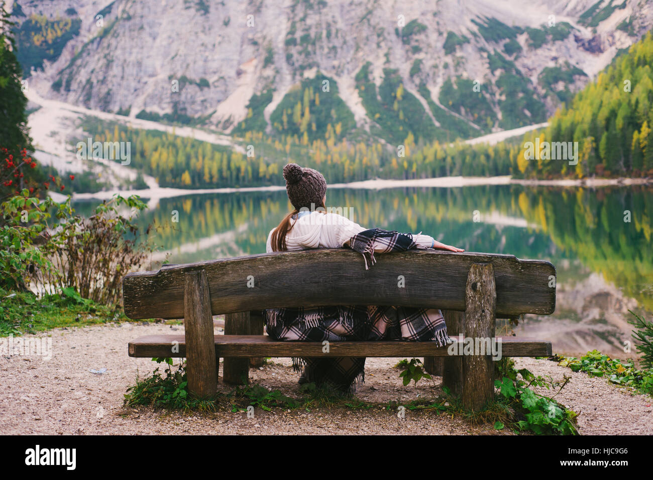 Donna relax su una panchina nel parco, Lago di Braies, Alpi Dolomitiche, Val di Braies, Alto Adige, Italia Foto Stock