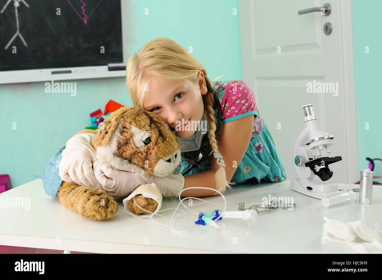 Ritratto di ragazza fingendo di essere vet abbracciando toy tiger con gocciolamento endovenoso Foto Stock