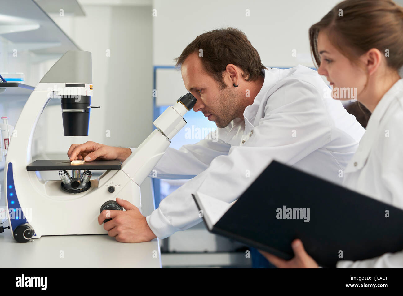 Scienziato in laboratorio guardando attraverso il microscopio Foto Stock