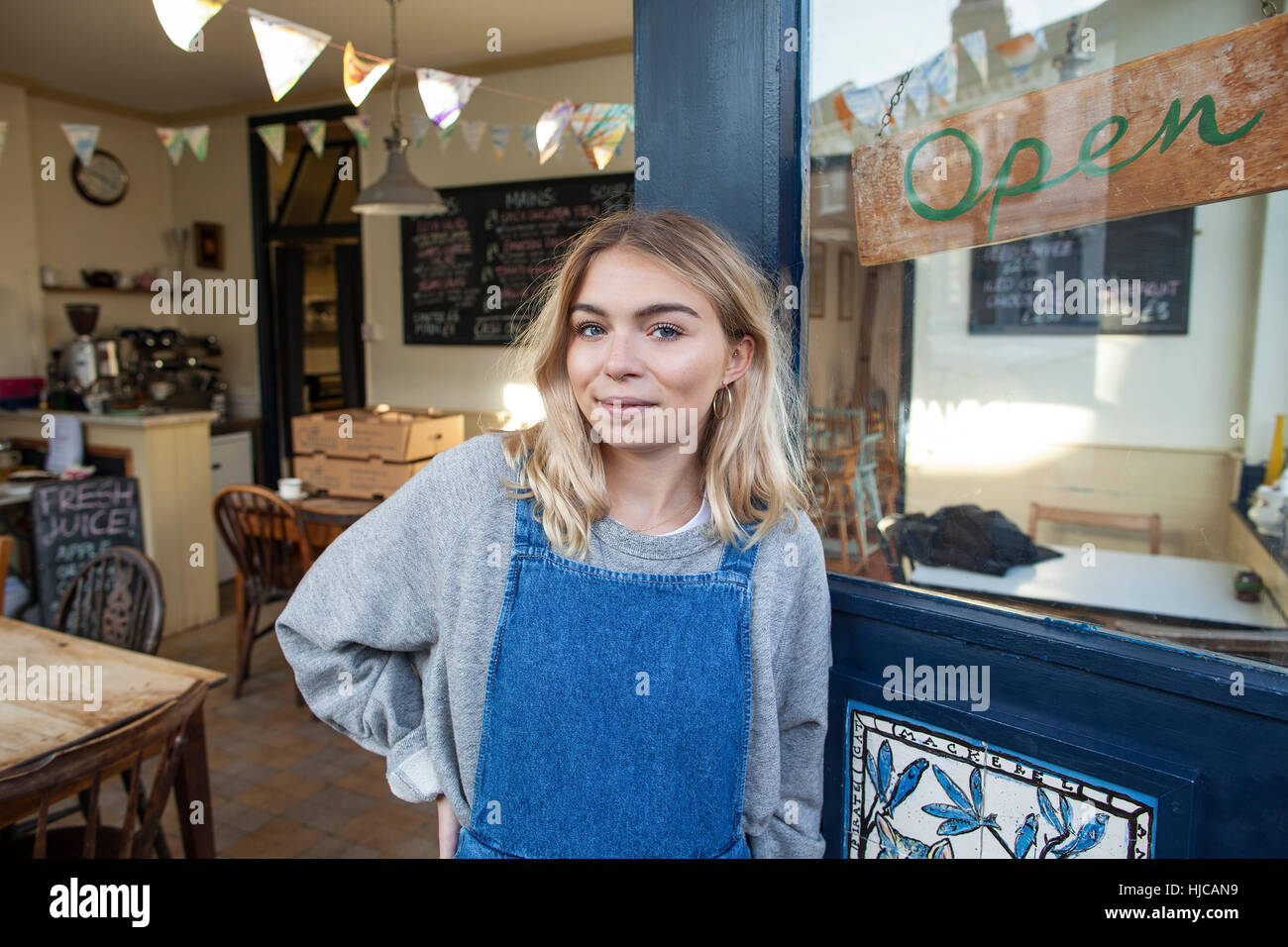 Ritratto di giovane donna in piedi nella porta di cafe Foto Stock