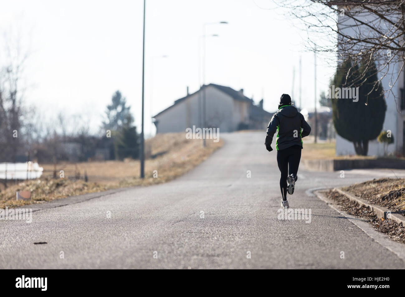 Vista posteriore di una donna in corsa per le strade di una cittadina in inverno o in autunno Foto Stock