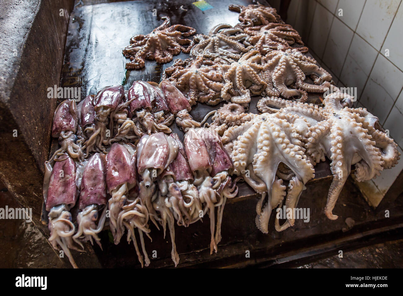 Piatti a base di frutti di mare freschi (octopus,calamari) per la vendita nel mercato di Darajani su bagnato scrivania in legno, pescato del giorno,Stone Town Zanzibar, Tanzania Africa Foto Stock