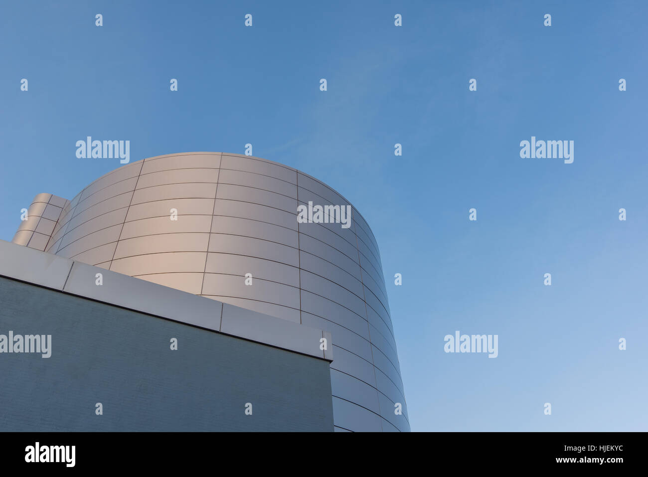 Un round argenteo vaschetta olio per stoccaggio di petrolio e un edificio quadrato in una centrale termoelettrica. Profondo cielo blu come sfondo. Foto Stock