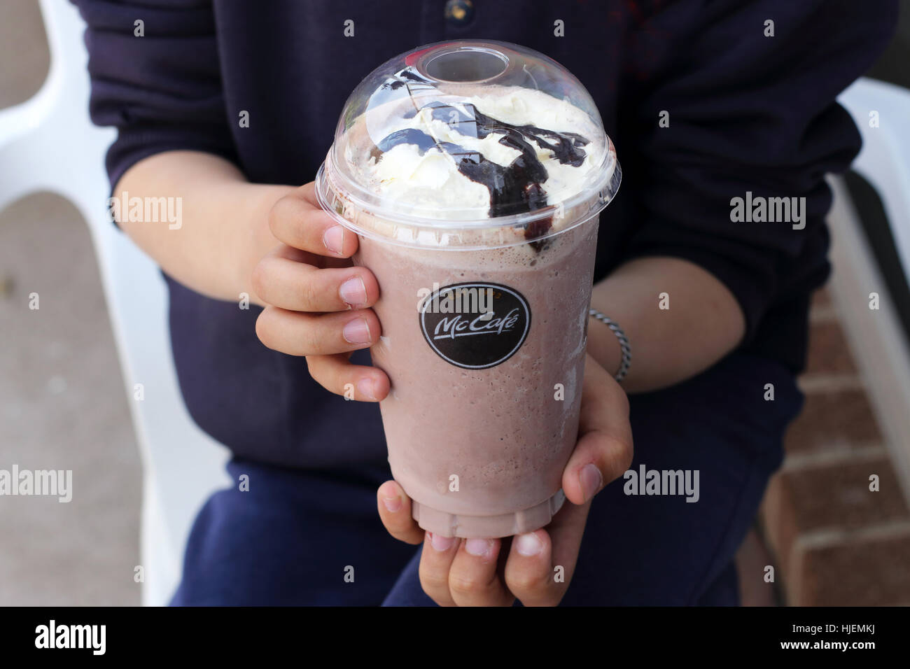 Close up di un bambino holdin McDonald Frappé al cioccolato con crema e salsa al cioccolato - McDonald's Melbourne Victoria Australia Foto Stock