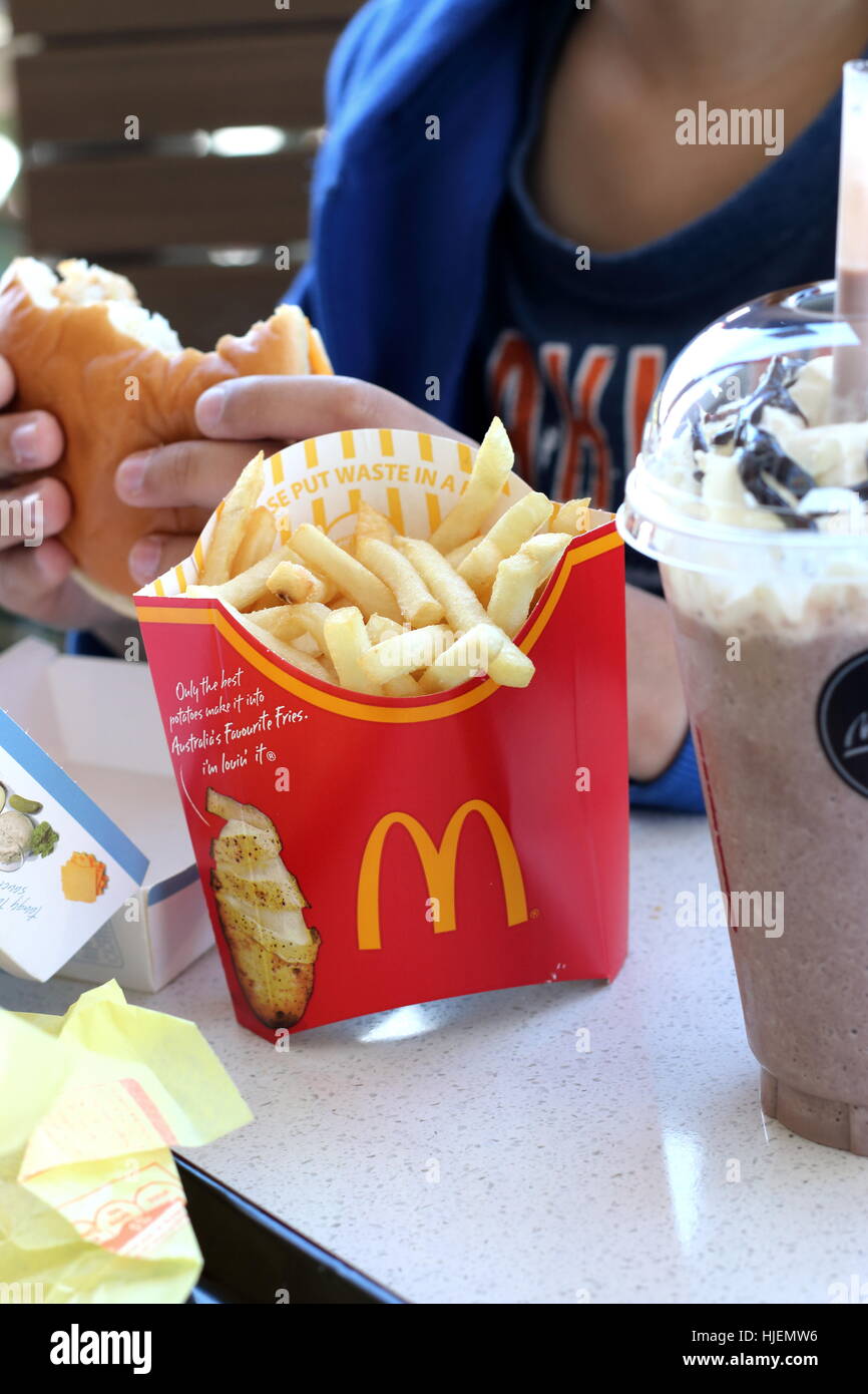Bambino mangiare Filetto di pesce hamburger e patatine fritte di patate al McDonald's Australia Foto Stock