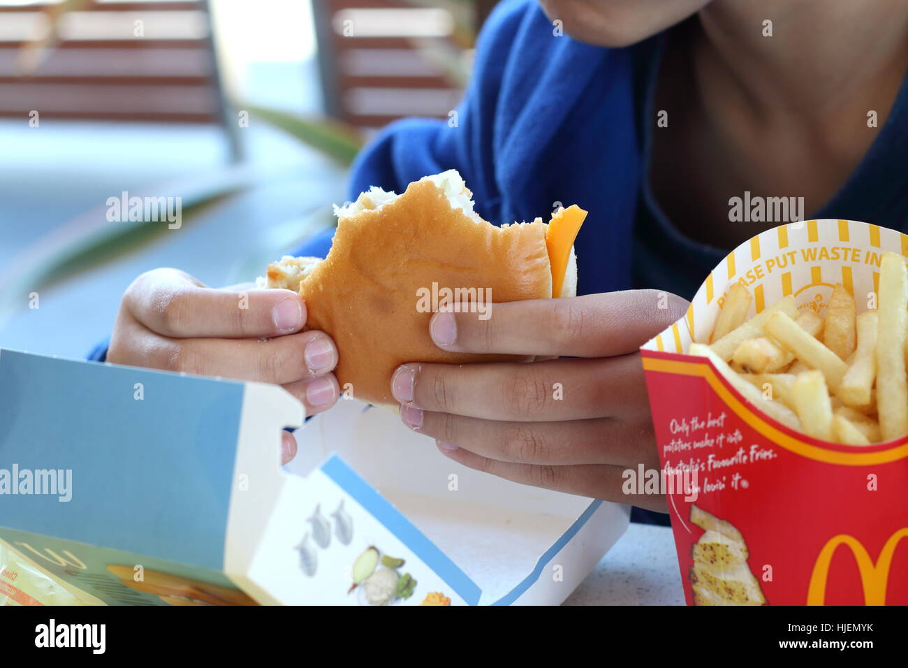 Un bambino mangiare Australian McDonald's Filet-o-hamburger di pesce e patatine fritte Foto Stock