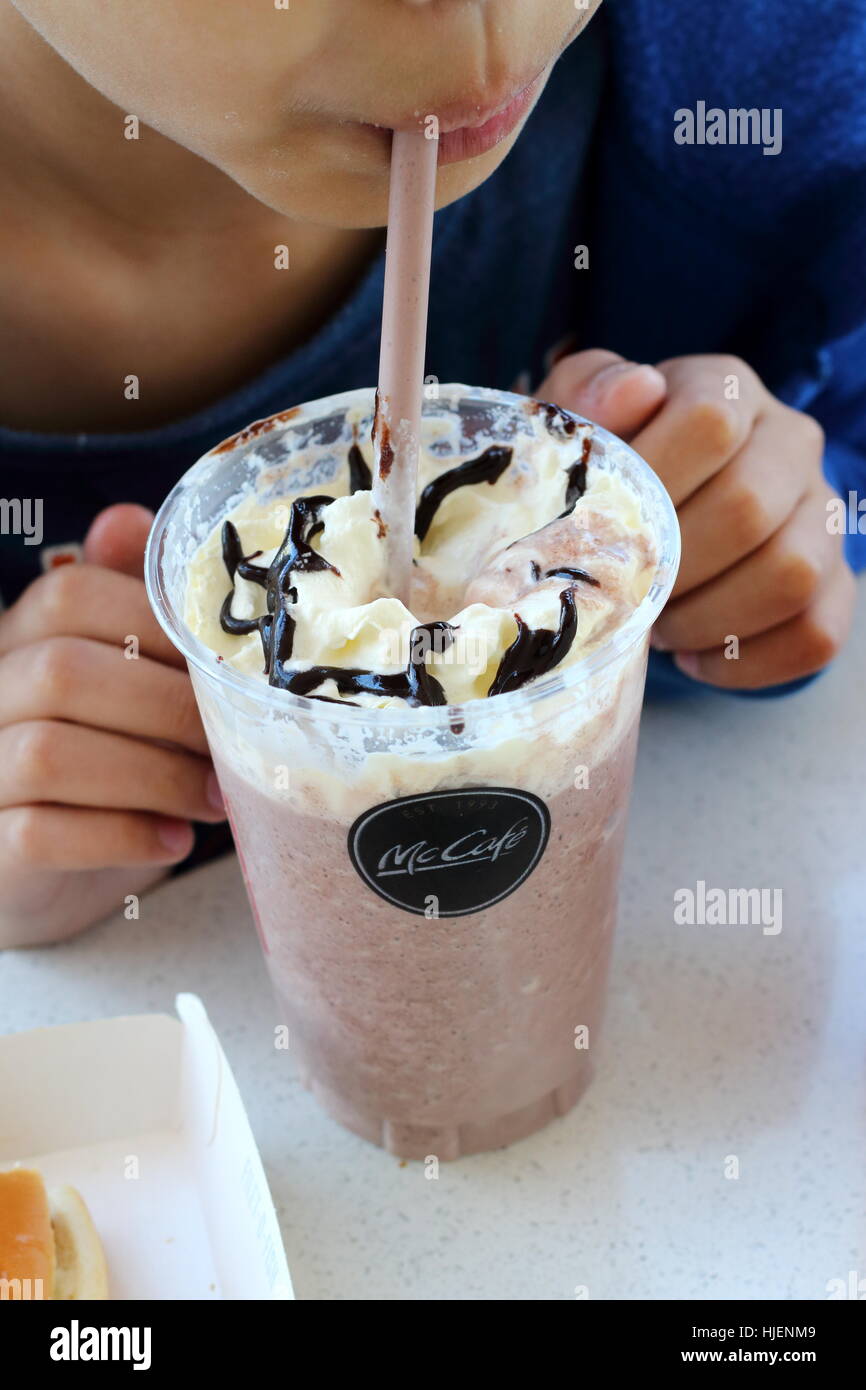 Close up di un bambino bere McDonald's chocolate Frappe in McDonald's Melbourne Victoria Australia Foto Stock