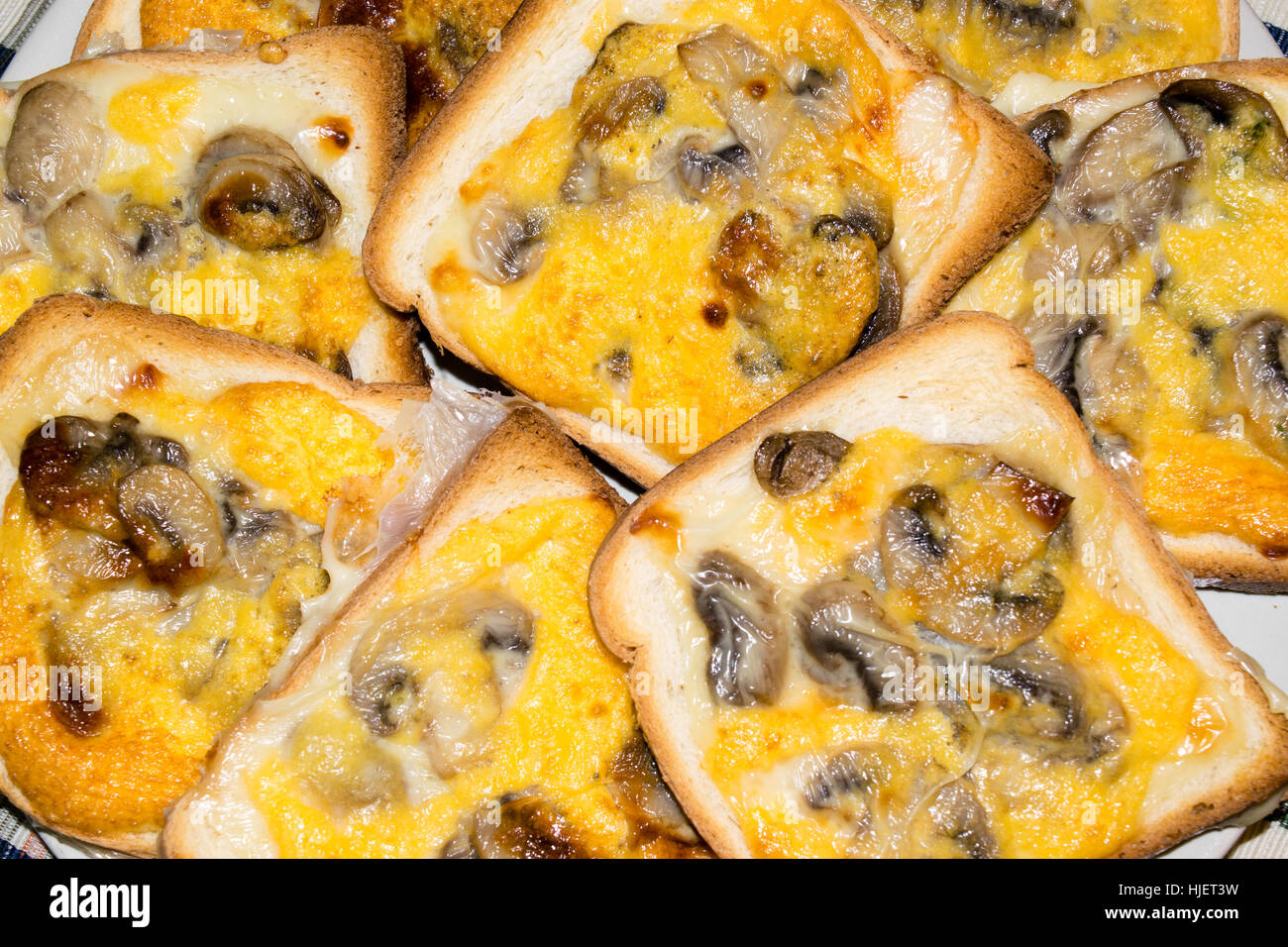 Fette di pane abbrustolito il pane bianco e condito con funghi, formaggio e uova Foto Stock