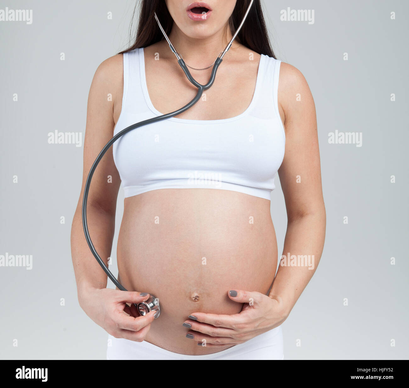 Donna incinta ascolta per la pancia da uno stetoscopio Foto Stock