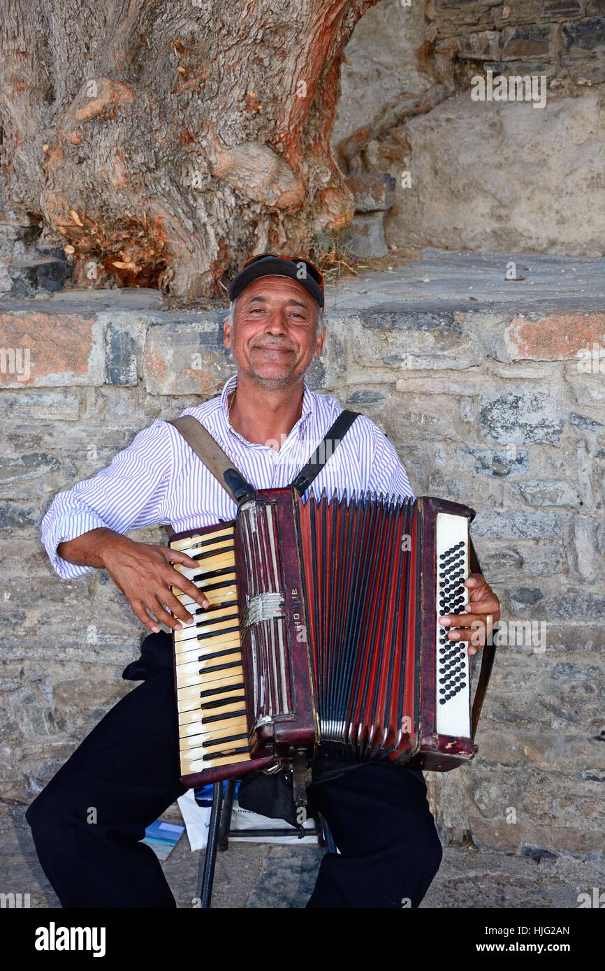 Uomo cretese suonare la fisarmonica a piano nel porto, Agios Nikolaos, Creta, Grecia, l'Europa. Foto Stock