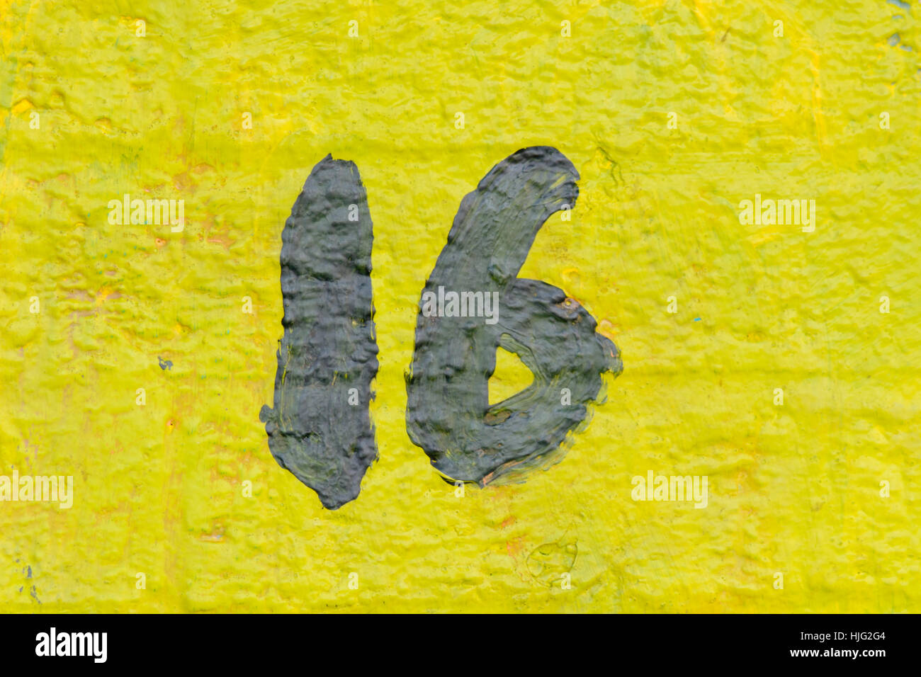 Il numero civico 16 segno dipinto di nero con sfondo giallo Foto Stock Il numero civico 16 segno dipinto di nero con sfondo giallo Foto Stock