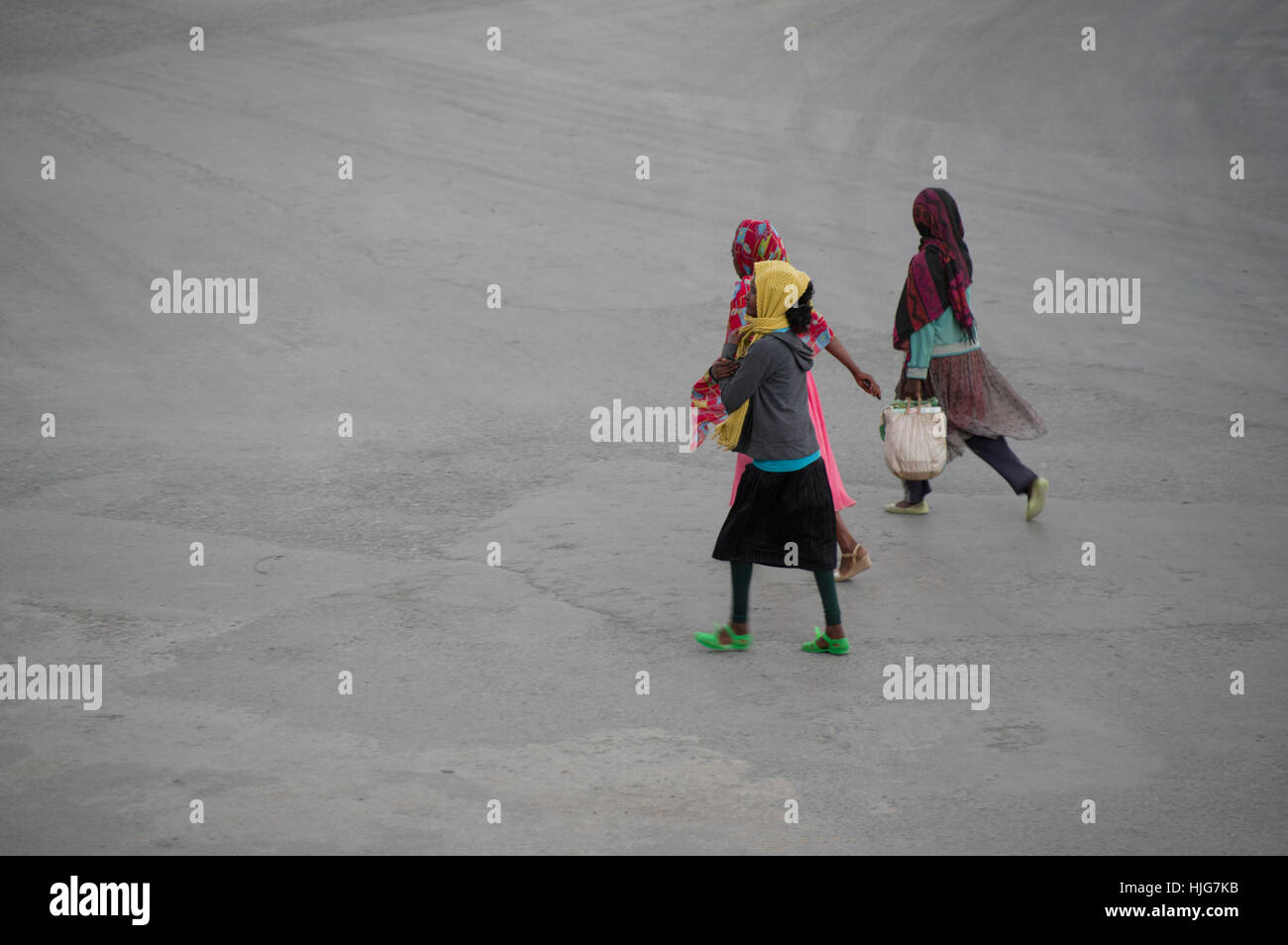 Tre donne camminando per la strada di Mekelle, Etiopia, uno con un cestello, tutti e tre i testa indossa foulard, volti non visibile Foto Stock