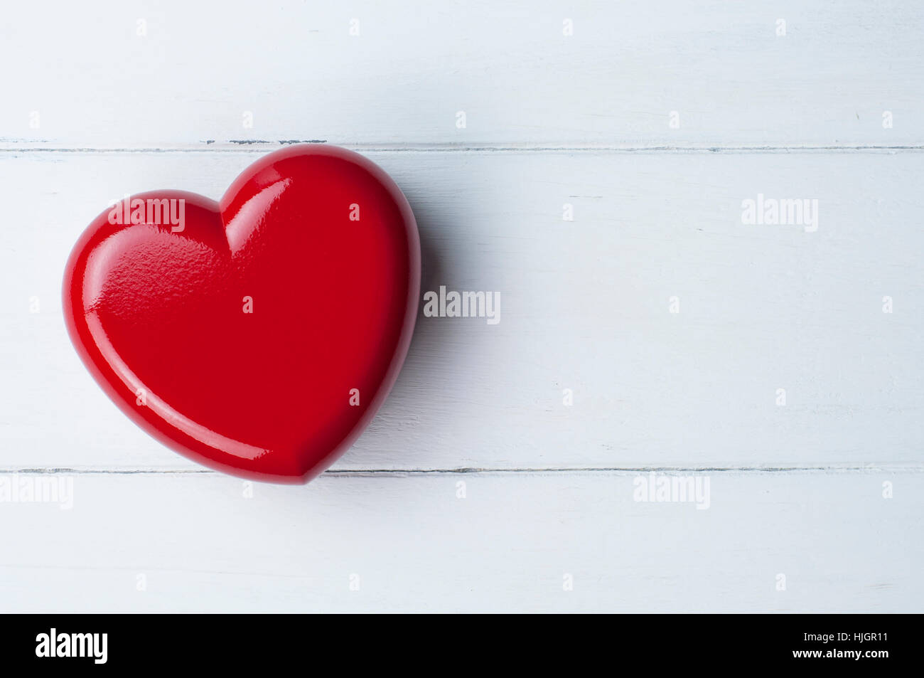 Cuore rosso su bianco sullo sfondo di legno. Amore e concetto di San Valentino. Vista superiore cuore rosso con copia spazio. Foto Stock