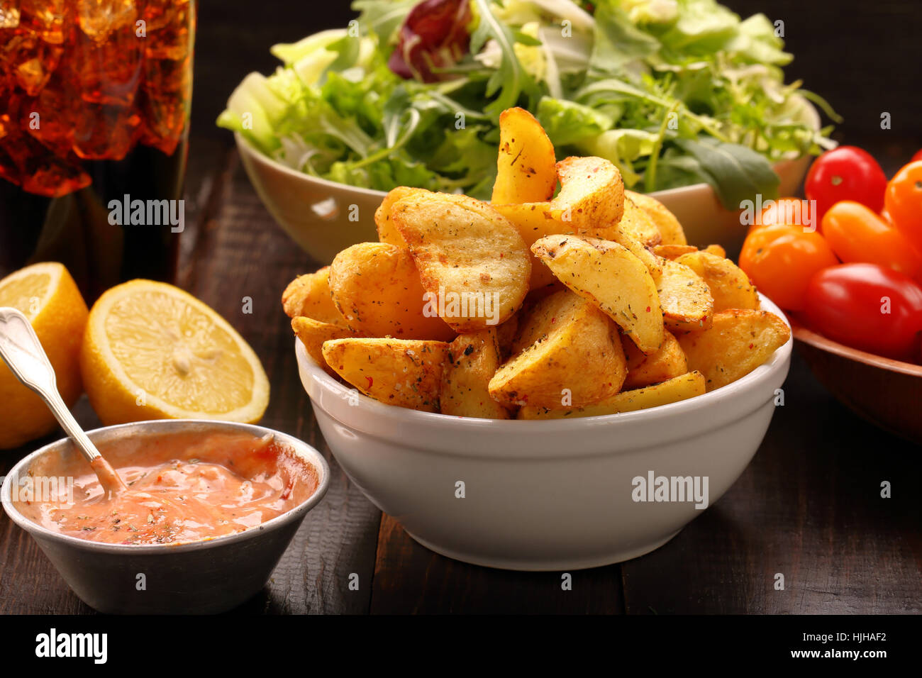 Patate arrosto con dip e insalata fresca sul tavolo di legno Foto Stock