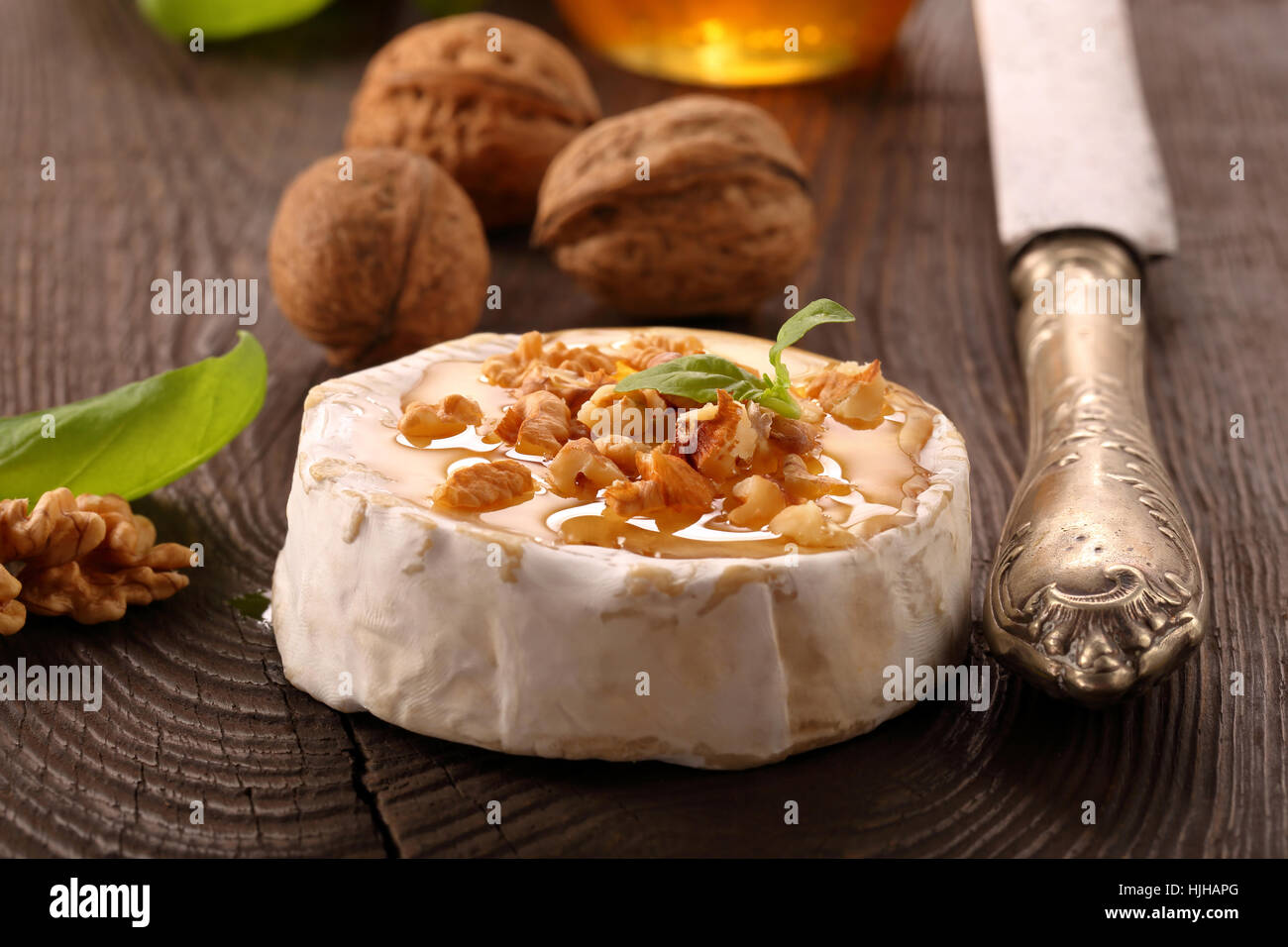 Grigliata di formaggio brie con il miele e i dadi sul vecchio sfondo di legno Foto Stock