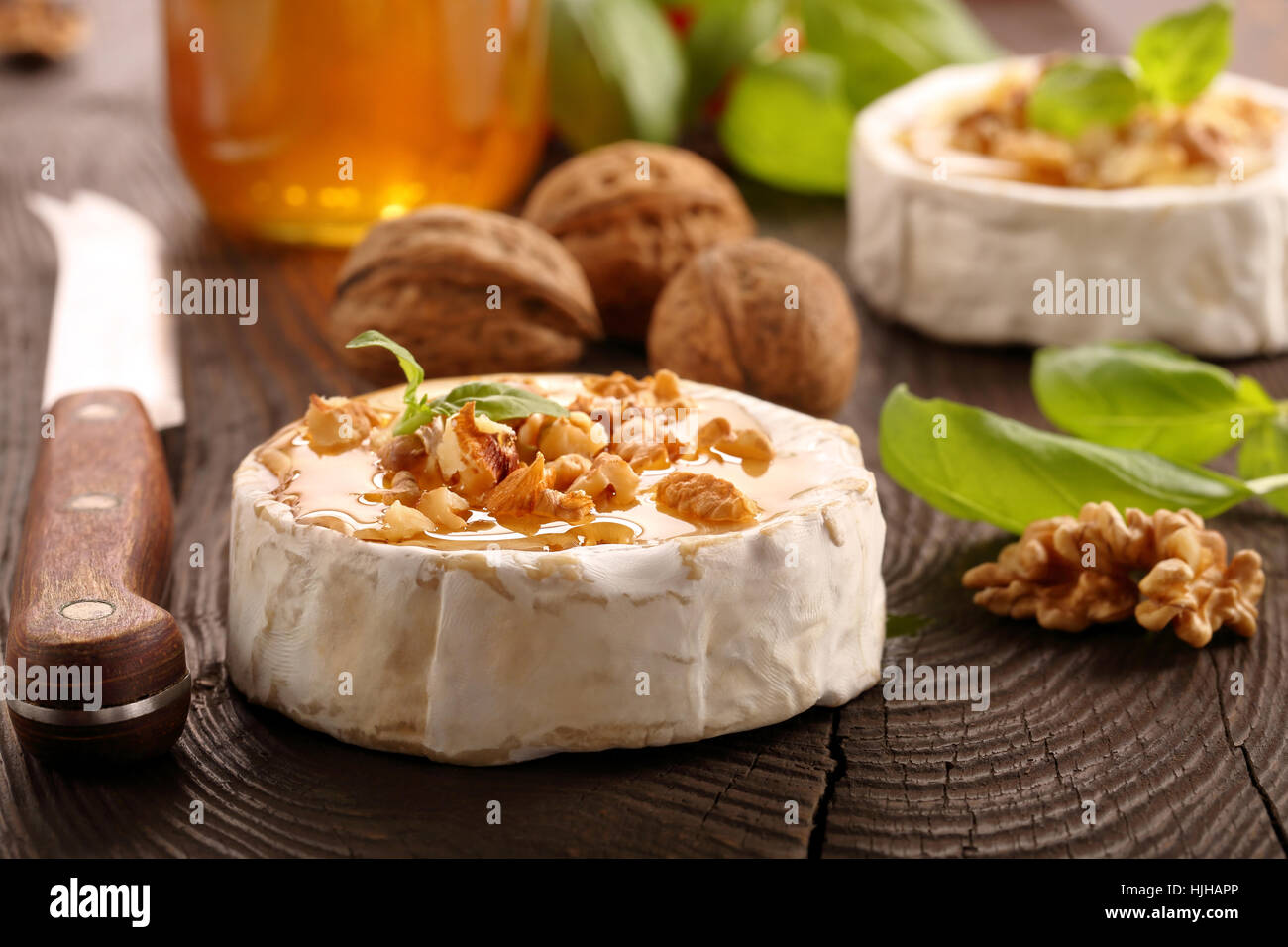 Grigliata di formaggio brie con il miele e i dadi sul vecchio sfondo di legno Foto Stock