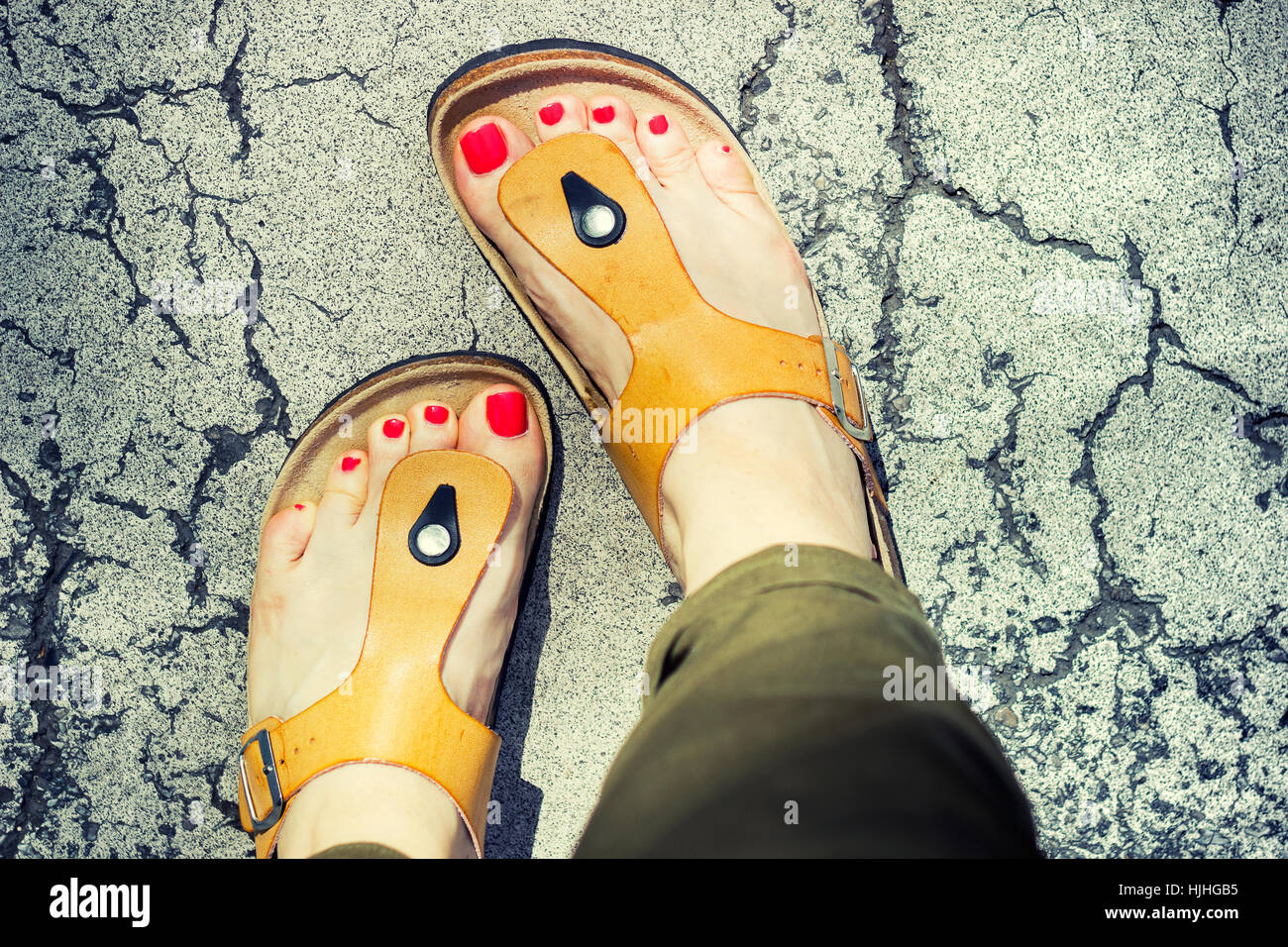 Donna di piedi in giallo elegante sandali estivi con rosso smalto per  unghie, in piedi su un pavimento rotto in una calda giornata estiva Foto  stock - Alamy