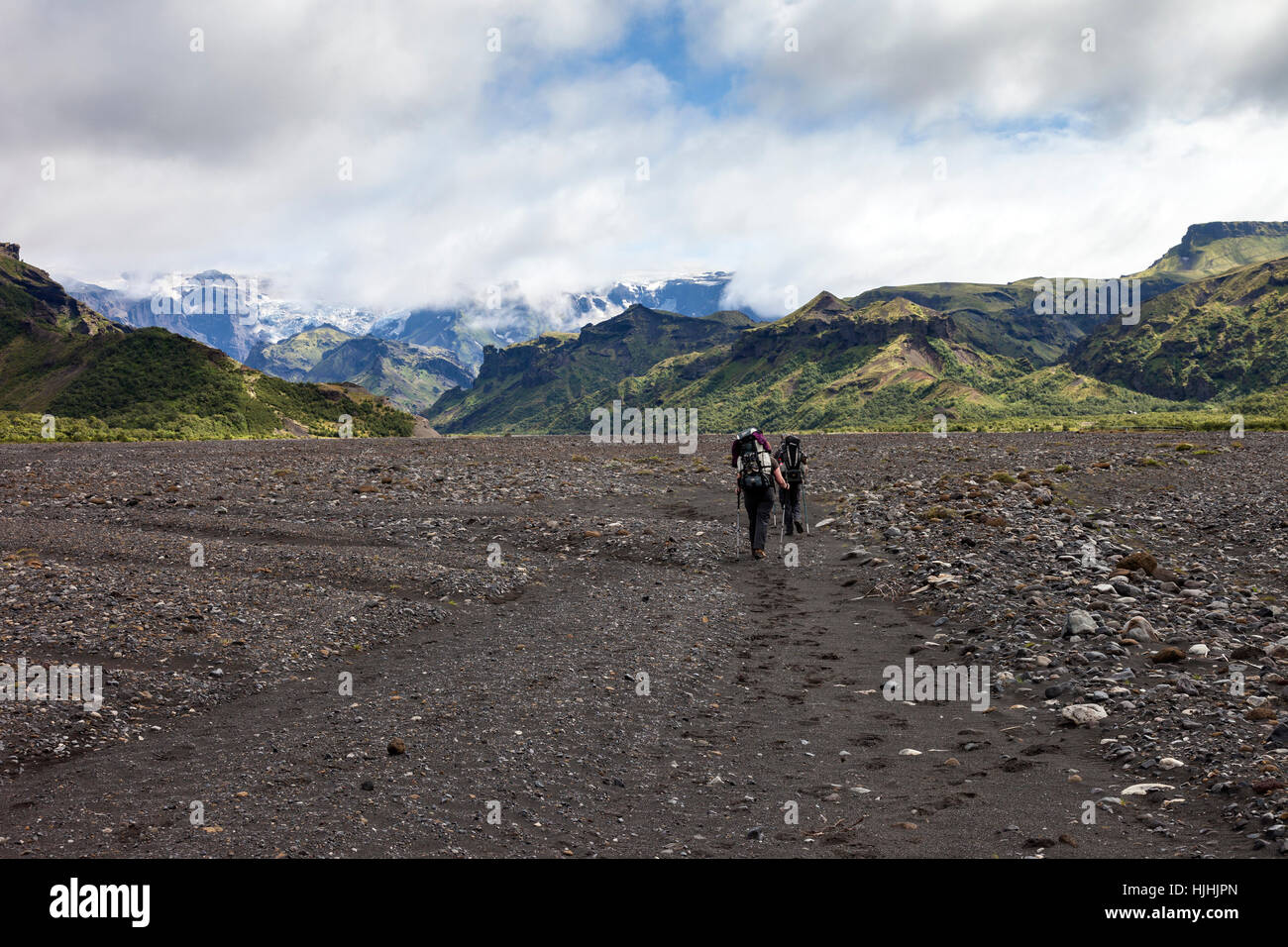 Gli escursionisti che attraversa il fiume Krossa pianura alluvionale con il Myrdalsjokull Icecap davanti, sotto il quale si trova il vulcano Katla, Islanda Foto Stock