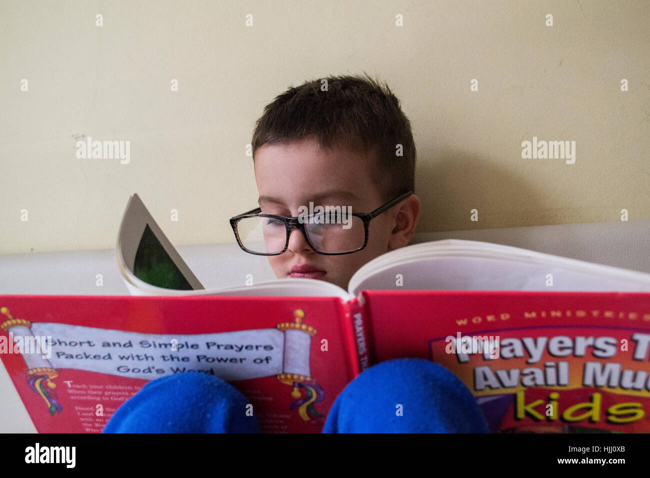 Ragazzino con gli occhiali per leggere un libro Foto Stock