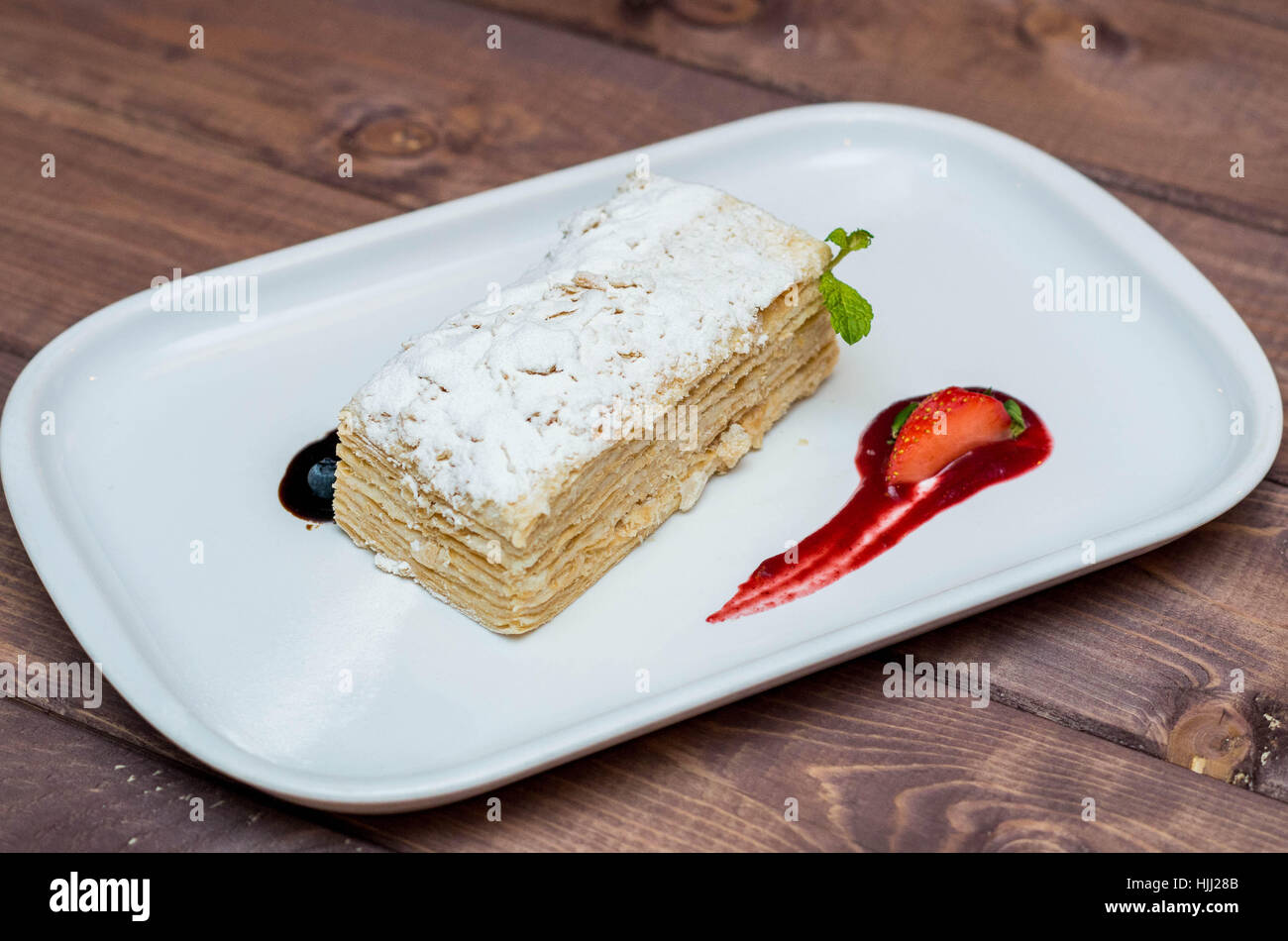 Bella e deliziosi dessert millefoglie con frutti di bosco su una piastra bianca con salsa, bellissimo ristorante offerta Foto Stock