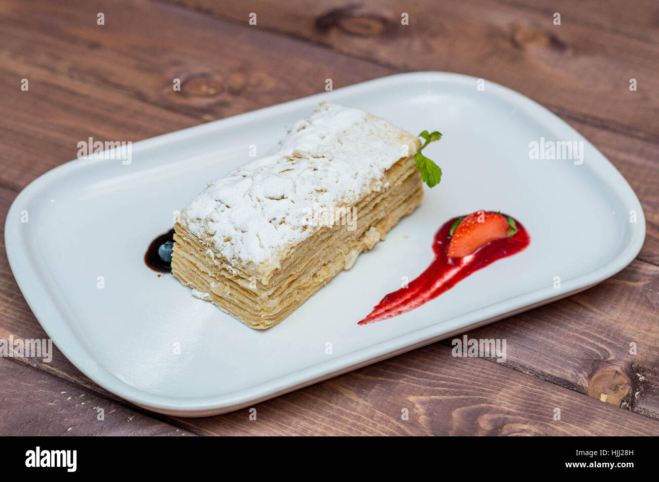 Bella e deliziosi dessert millefoglie con frutti di bosco su una piastra bianca con salsa, bellissimo ristorante offerta Foto Stock