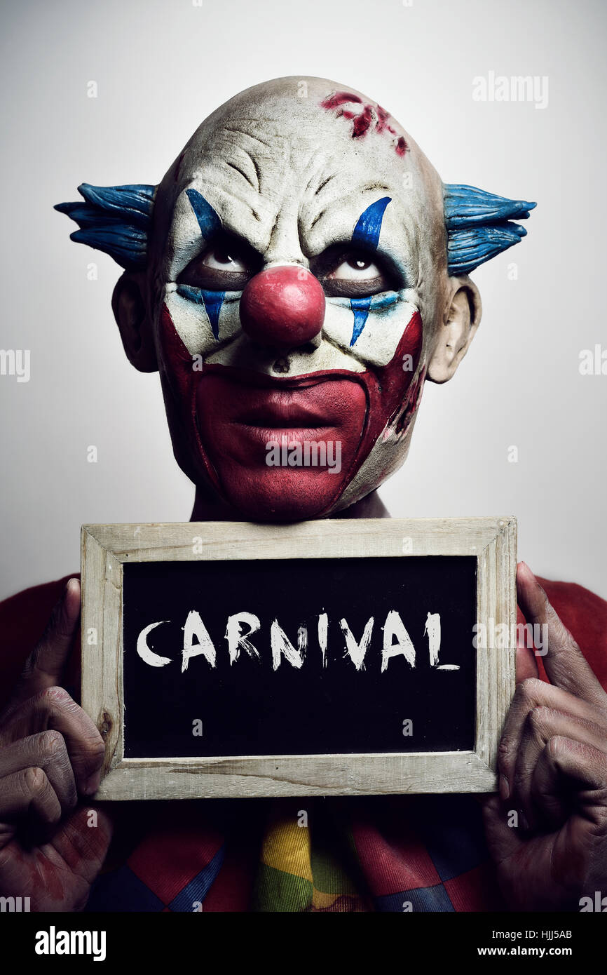 Ritratto di un male spaventoso clown con una lavagna con la parola scritta di carnevale in esso Foto Stock